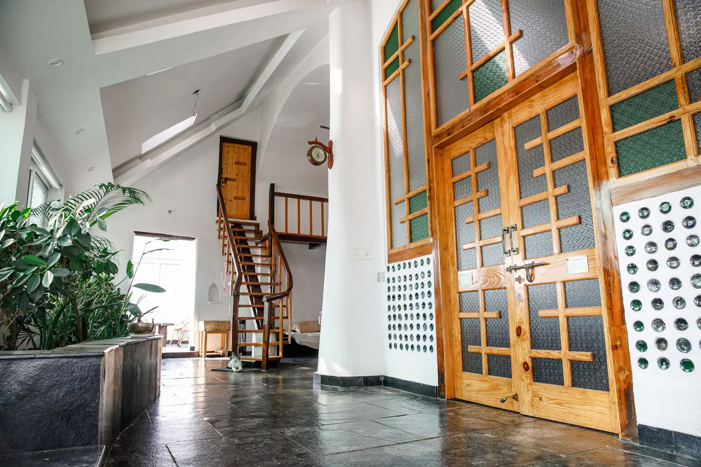 Earthship entrance hall with spiral staircase and glass bottle walls