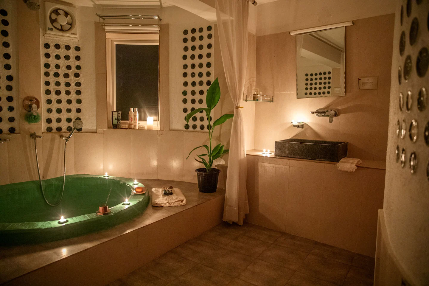Spa bathroom with green bathtub, candles, and glass bottle walls
